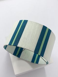 a white and blue striped cuff sitting on top of a piece of paper