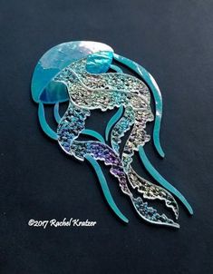 an image of a jellyfish brooch on a black surface with blue and purple colors