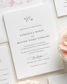 the wedding stationery is laid out on top of each other, with pink flowers