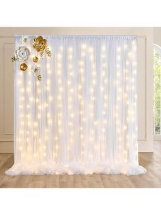 a white curtain with lights on it and flowers hanging from the side, in front of a