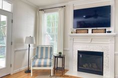 a living room with a fireplace, television and chair in front of the fire place