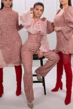 three women in pink and red outfits posing for the camera with one woman sitting on a chair