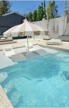 an empty swimming pool with lounge chairs and umbrellas