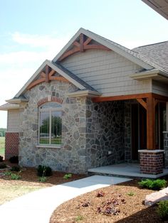 a house with stone and wood trim on the front door is shown in this image