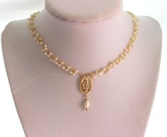 "This is a gold Miraculous Medal Pearl Choker Necklace for women. Absolutely elegant! This necklace is made with 2-3mm fresh water pearls on 24kt gold plated wire, a 14kt gold filled medium size Miraculous medallion 20x13mm at it's center with a Pearl drop. Necklace is adjustable 2\" with a spring clasp in back. Model is wearing a 14\"-16\" length. Comes nicely boxed, the perfect gift! Maybe ordered in 925 Sterling silver." Gold Pearl Necklace With Spiritual Charm, Spiritual Gold Pearl Necklace With Pearl Charm, Spiritual Gold Pearl Necklace With Charm, Spiritual Gold Necklaces With Pearl Drop, Spiritual Gold Necklace With Pearl Drop, Gold Spiritual Necklace With Pearl Drop, Gold Pearl Necklace As A Meaningful Gift, Spiritual Gold Pearl Drop Necklace, Catholic Jewelry Necklace