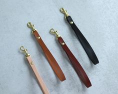 three different colored leather lanyards on a white surface