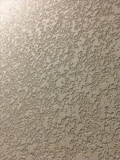 the texture of an old wall is white and has small dots on it's surface