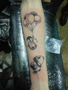 an arm with some tattoos on it and balloons in the shape of animals flying through the air