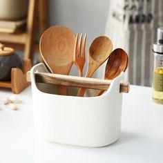 wooden utensils in a white container on a table