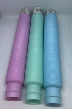 four different colored cups sitting next to each other on a white counter top in a row