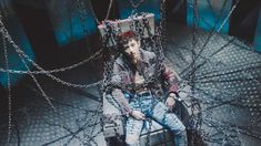 a man sitting on top of a chair covered in chains