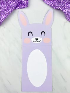 an easter bunny treat bag on a marble table with purple and white decorations around it