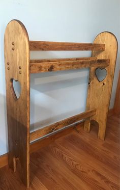 a wooden bed frame with hearts cut out of the top and bottom, sitting on a hard wood floor