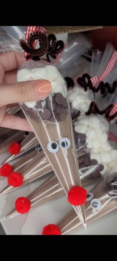 someone is holding up some candy sticks with googly eyes on them and red pom - poms