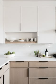 a kitchen with white cupboards and wooden cabinets in the center, along with two bowls on the countertop