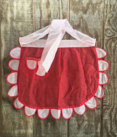 a red and white dress hanging on a wooden wall