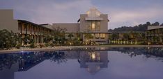 a large building with a pool in front of it at night time and lights on the windows