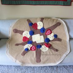 a crocheted blanket with stuffed animals on it sitting on a couch next to an american flag