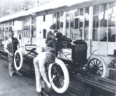 an old black and white photo of men working on the wheels of a steam engine