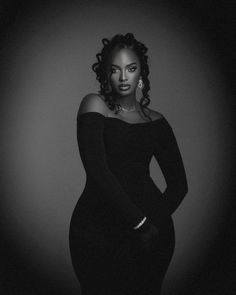 a black and white photo of a woman in a dress with her hands on her hips