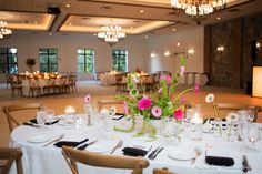 a table set up for a formal function with flowers and candles on the centerpieces