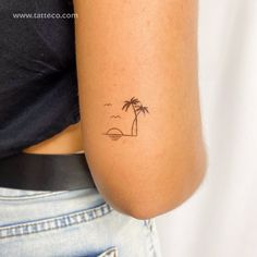 a small palm tree tattoo on the back of a woman's left arm,