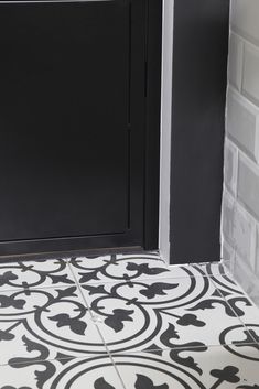 a black and white tile floor next to a door with an ornate design on it