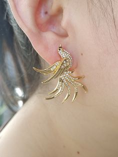 These bird studded gold fashion earrings are the perfect combination of style and elegance. The exquisite design is inspired by the agility of nature, as if a light and flying bird is singing happily in the ear. The earrings are made of high-quality gold alloy and are inlaid with sparkling crystal diamonds. Each one emits a dazzling light, as bright as morning dewdrops. The golden luster adds a sense of luxury to the entire earrings, complementing the sparkle of the diamonds, making the wearer exude confidence and charm. Whether paired with everyday casual wear or an evening gown, these earrings will add a pop of color to your look. It is not only a fashion accessory, but also a perfect symbol of personal taste and style. Whether you are on the cutting edge of fashion or seeking timeless c Flying Bird, Comme Si, Gold Alloys, Birds Flying, Sparkling Crystal, Diamond Crystal, Gold Fashion, Unique Earrings, Exquisite Design