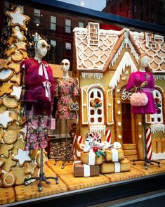 a window display with gingerbread houses and other holiday decorations in the front, along with mannequins