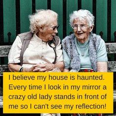 two elderly women sitting on a bench with a sign saying i believe my house is haunted every time i look in my mirror a crazy old lady stands in front of me