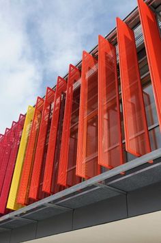 an orange and yellow building with many different colored doors on it's side, against a blue sky