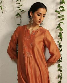 Editor's Note The timelessness of nature inspired motifs is interpreted through hand embroidered leaf motifs in this orange relaxed fit kurta set. The decadence is enhanced with our intricate nakshi and zari work. A beautiful nakshi work organza cut-out chanderi dupatta and scalloped edged narrow pants lend a glamorous touch to the overall look Fabric: Kurta: chanderi, pant: cotton satin, dupatta: organza Color: Orange Component: Kurta, pant and dupatta Occasion: Festive Note: Product colour may Satin Dupatta, Simple Kurtis, Chudidhar Neck Designs, Kurta And Dupatta, Embroidered Leaf, Chanderi Dupatta, Kurta Patterns, Simple Kurta Designs, Upcycling Ideas