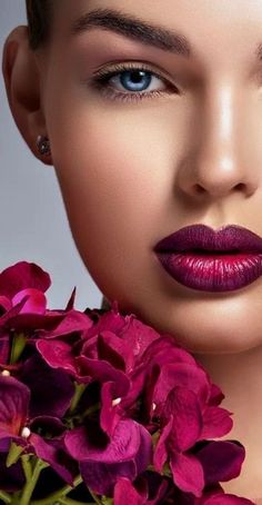 a woman with purple lipstick and flowers in her hair is looking at the camera while she holds