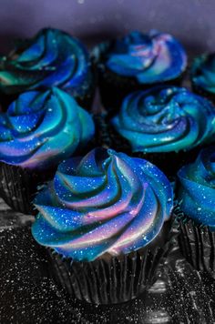 there are many cupcakes with blue frosting on the top and purple icing on the bottom