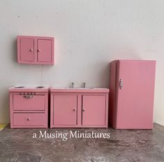 a pink refrigerator and sink are next to each other on the floor in front of a white wall