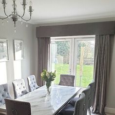 a dining room table with chairs and a chandelier in front of a window