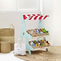 a small wooden stand with baskets and bags on the floor next to it, along with other items