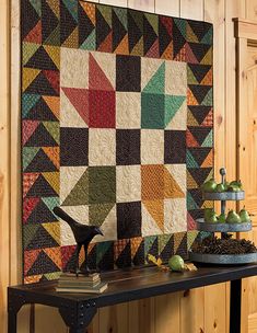 a table topped with a quilt next to a wall