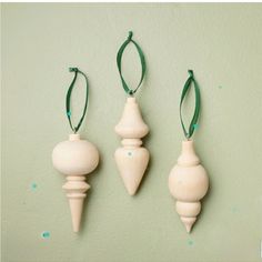 three wooden ornaments hanging on a green wall