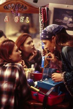 two women are talking to each other in front of a mirror with jewelry hanging from it