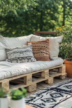 a couch made out of wooden pallets on a deck with plants in the background