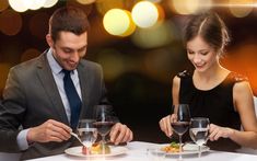 a man and woman sitting at a table with wine glasses in front of each other