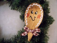 a wooden spoon with a face drawn on it hanging from a christmas tree ornament