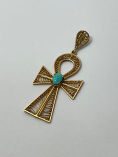 A vintage 18K gold cross pendant featuring one 7.7mm x 5.7mm cabochon cut turquoise stone complemented by delicate gold wire designs. This item weighs 6.5 grams with a length of 2.5 inches, the bail fits a 4mm chain. Elegant Turquoise Cross Jewelry, Gold Cross Pendant, Gold Cross, Gold Wire, Turquoise Stone, Cross Pendant, 18k Gold, Turquoise, Chain