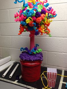 a colorful tree made out of plastic letters on top of a red bucket filled with popcorn