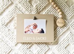 a photo frame with a baby's hand and name hanging from it on a white blanket