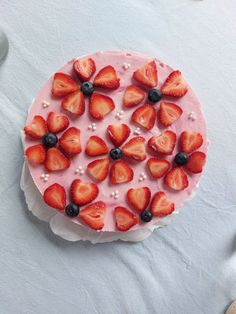 there is a cake with strawberries and blueberries on the frosting in the shape of a circle