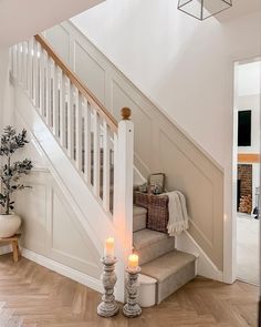 two lit candles are sitting on the stairs in this white room with wood flooring