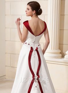 a woman in a white and red wedding dress standing next to a pillar with her hand on her hip