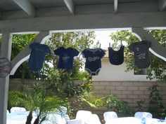 baby clothes hanging from a pergolated area with tables and chairs in the background